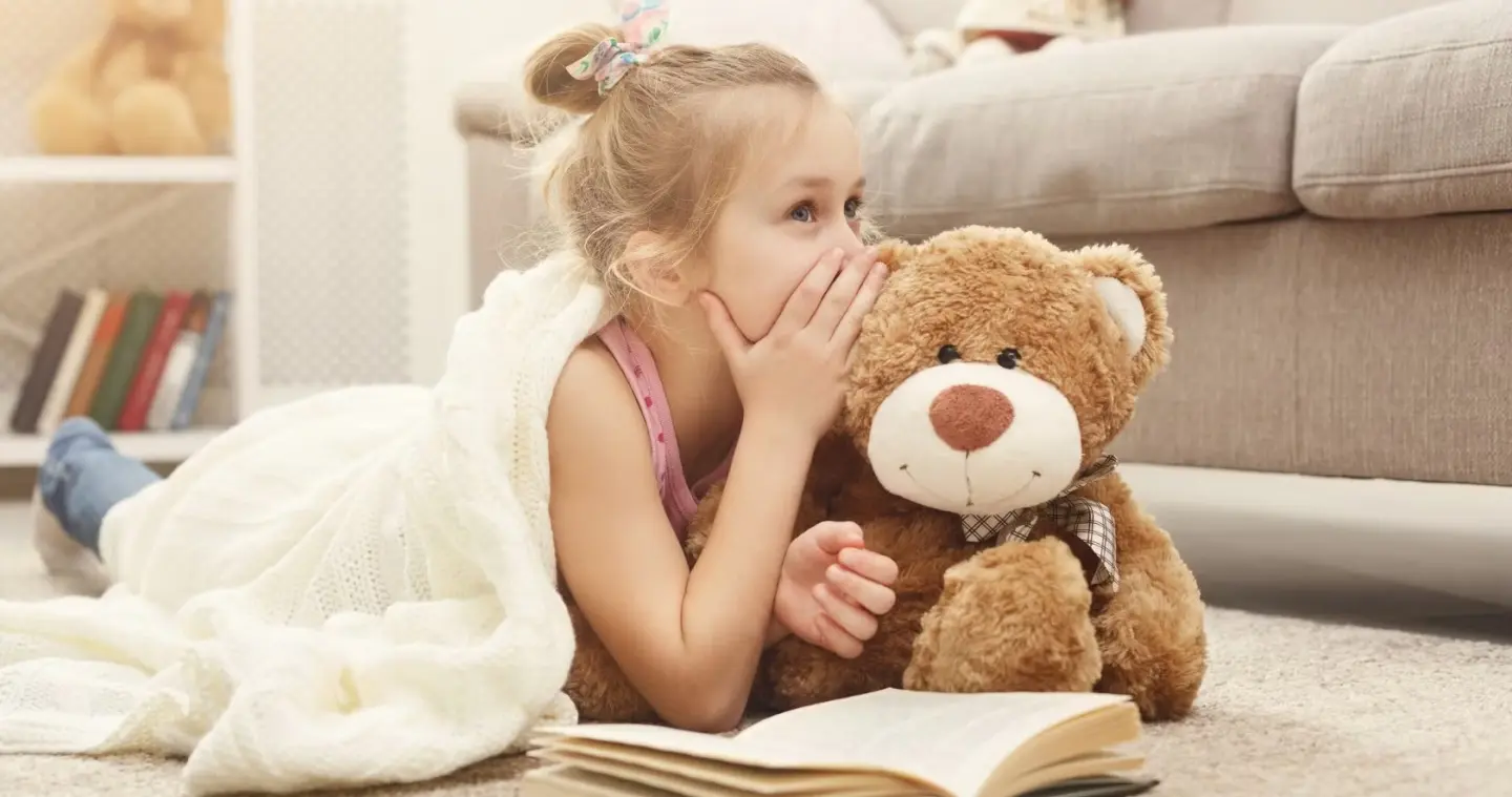 happy-little-female-child-and-her-teddy-bear-reading-book-on-the-at-picture-id932263376.jpg